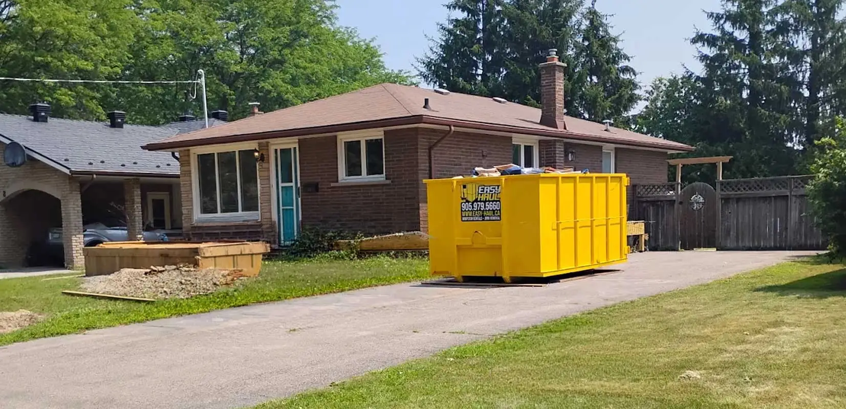 Roll-off dumpster bin on a Kitchener residential driveway with wood blocking protection